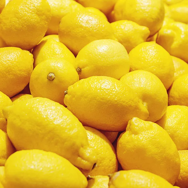 Sarı limonlar meyve pazarında kapanıyor, parlak limon arka planda