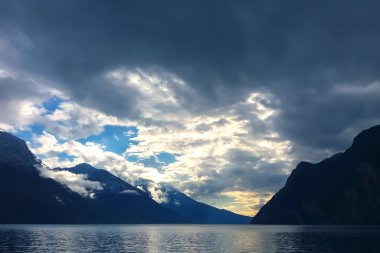 Mavi alacakaranlıkta fırtınalı gökyüzünde dramatik bulutlarla dolu dağ gölü