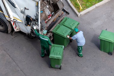 Çöpçüler çöpleri çöp kamyonuna yüklüyorlar, yukarıdan bakıyorlar.