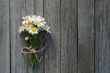 Vahşi papatya buketi ahşap arka planda kenevir ipiyle bağlanmış.