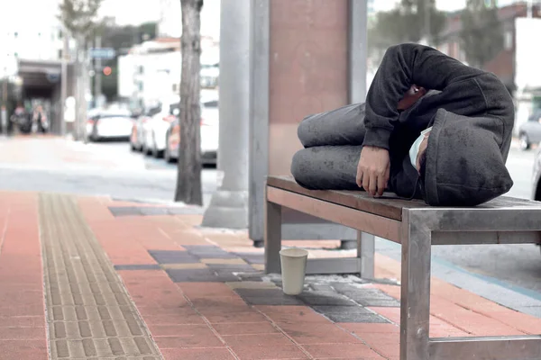 ホームレスの男や難民が街の歩道の木製のベンチで寝ている — ストック写真