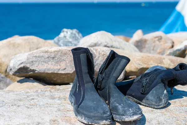 Tauchstiefel trocknen auf einem Stein. Eine Tauchfahne und blaues Wasser im Hintergrund — Stockfoto