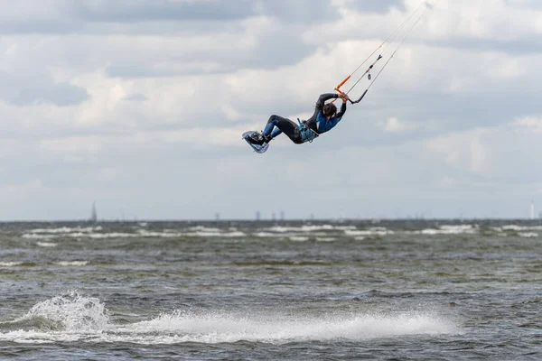 Een kitesurfer springt hoog in het water op een winderige dag vele wanneer veel mensen van de gelegenheid gebruik maken om watersporten te beoefenen. Kitesurfers verzamelen zich bij het strand van Lomma — Stockfoto