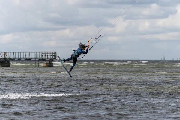 Een kitesurfer springt hoog in het water op een winderige dag vele wanneer veel mensen van de gelegenheid gebruik maken om watersporten te beoefenen. Kitesurfers verzamelen zich bij het strand van Lomma — Stockfoto