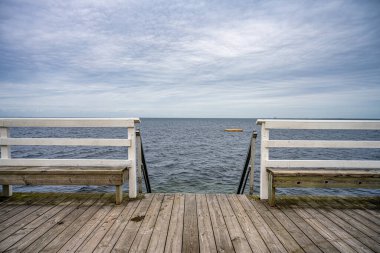 Arka planda mavi okyanus ve gökyüzü olan ahşap bir iskele. Fotoğraf: Malmö, İsveç