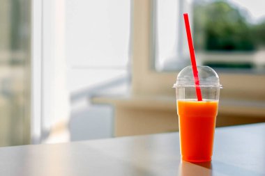 Plastik bardakta portakal suyu ve pipet.