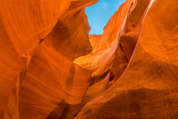 The high walls of the canyon restrict light from the blue sky above in lower Antelope Canyon, Page, Arizona