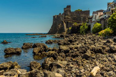 Yazın Sicilya, Acicastello 'daki Norman şatosu ve kayalık kıyı şeridi.
