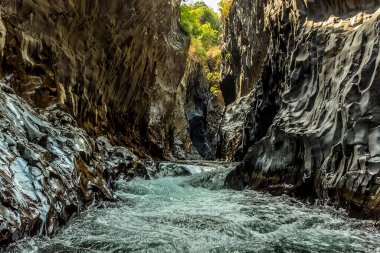 Kaygan duvarlar ve hızlı akan bir Alcantara nehri Sicilya 'nın Taormina yakınlarındaki Alcantara geçidinde, bazalt volkanik kolonların dar boşluklarından akar.