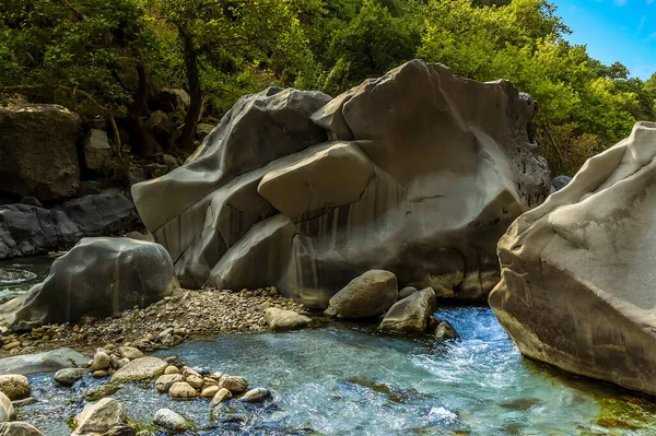 Large volcanic boulders impede the course of the Alcantara river near Taormina, Sicily in summer