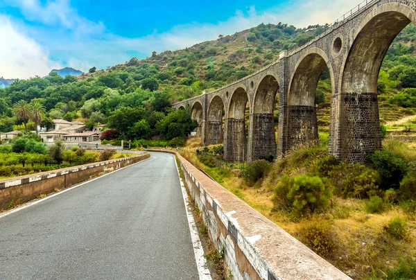 A road bridge and an abandoned railway bridge cross the Alcantara river near Taormina, Sicily in summer