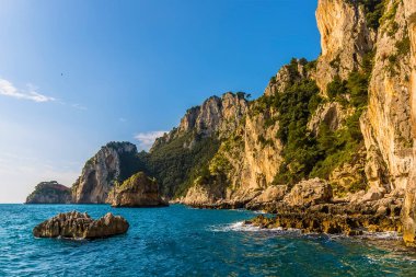 İtalya 'nın Capri adasının doğu kıyısı boyunca uzanan kumtaşı kayalıkları ve deniz yığınları.