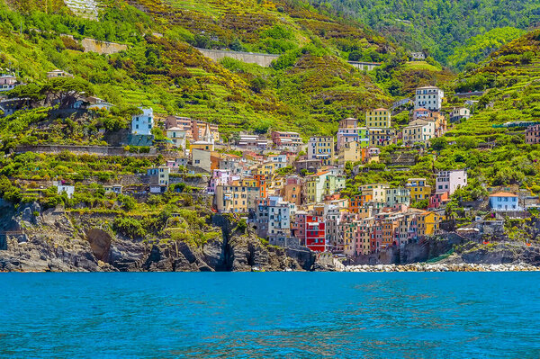 A view from the sea towards the Cinque Terre coast and the village of Riomaggiore, Italy in the summertime