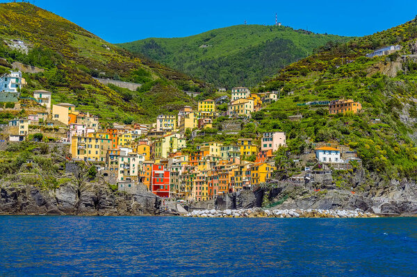 A panorama view from the sea across the harbour breakwater towards the Cinque Terre village of Riomaggiore, Italy in the summertime