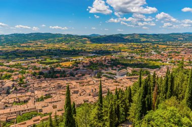 Colle Eletto teleferiğinden İtalya 'nın Gubbio katedrali üzerinden yazın Apennine dağlarına doğru ağaç hattının üzerinde bir manzara.