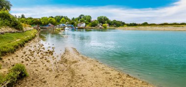 A panorama view down the River Ouse towards the village of Piddinghoe, UK in summer clipart