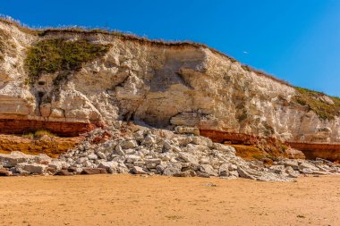 Yakın zamanda gerçekleşen beyaz tebeşir taşı düşüşü Old Hunstanton, Norfolk, İngiltere 'deki kayalıklardaki kırmızı ve turuncu katmanları kısmen gizliyor.