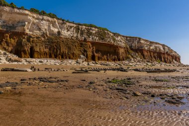 Old Hunstanton Sahili 'ndeki kumdan bir gemi enkazı Norfolk, İngiltere' deki beyaz, kırmızı ve turuncu katmanlı kayalıkların altına düştü.