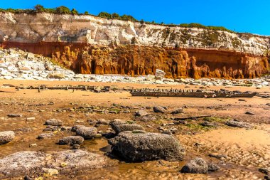 Old Hunstanton Sahili 'ndeki kumdan bir gemi enkazı Norfolk, İngiltere' deki beyaz, kırmızı ve turuncu katmanlı kayalıkların altına düştü.
