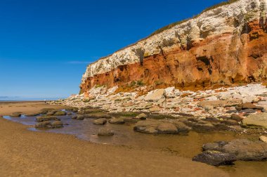 Tebeşir ve kumtaşı, Old Hunstanton, Norfolk, İngiltere 'deki beyaz, kırmızı ve turuncu katmanlı kayalıklardan aşınırken, renklerin kayalıkları.