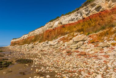 Old Hunstanton, Norfolk, İngiltere 'deki beyaz, kırmızı ve turuncu katmanlı kayalıklardan büyük kayalıkların manzarası