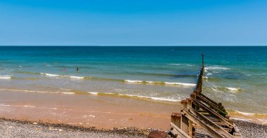 Sahil yolundan denize doğru bir manzara ufuk çizgisindeki rüzgar türbinlerine doğru Sheringham, Norfolk, İngiltere 'de.