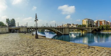 Guadalquivir nehrinin doğu kıyısından Seville, İspanya 'daki San Telmo köprüsüne doğru bir manzara.