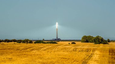 İspanya, Seville yakınlarındaki tarlalarda yaz mevsiminde güneş konsantrasyonu sağlayan bir enerji santraline doğru bir manzara.