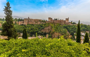 Granada 'nın Albaicin bölgesindeki ağaçların tepesinden Alhambra Sarayı ve Sierra Nevada dağlarına doğru bir manzara.