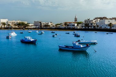 Arrecife, Lanzarote 'deki Charco de San Gines gölünde demirlemiş küçük tekne manzarası güneşli bir öğleden sonra San Gines kilisesine doğru bakıyor.