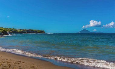 St. Kitts 'te sakin bir sahil boyunca Sint Eustatius adasının bulunduğu bir manzara.