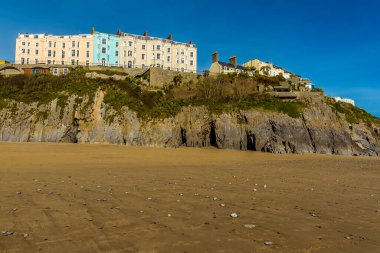 Güneşli bir günde Tenby, Pembrokeshire 'deki kayalıkların ve renkli otellerin güney sahili manzarası