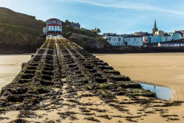 Güneşli bir günde Pembrokeshire, Tenby 'deki limana doğru eski bir filika istasyonunu geçince