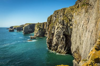 Galler 'in Pembrokeshire sahili boyunca uzanan manzarası bir Geo' nun girişini (çökmüş mağaranın sadece girişi kalmıştı), yazları kaya yığınları ve yamaçların yüzlerini göstermektedir.