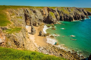 Yazın Galler 'in Castlemartin yakınlarındaki Pembrokeshire sahilinde rafları olan ıssız bir kumlu koy.
