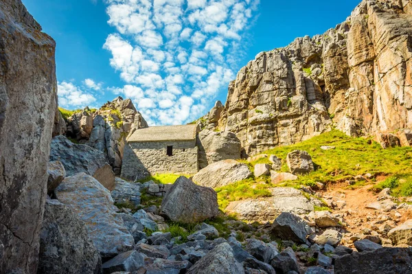 St. Govans Kilisesi 'nin kalıntıları. Yazın başında Pembrokeshire sahilinin arka planında sirrus bulutları oluşmuş.