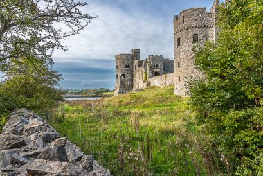 Kuru bir taş duvarla İngiltere 'nin Pembrokeshire kentindeki Carew Kalesi kalıntıları arasındaki Carew nehrine doğru bir manzara.