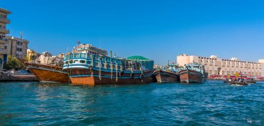 Bahar mevsiminde BAE 'deki Dubai Deresi' nde demirli dhow kargo gemileri ve Abra su taksilerinin görüntüsü.