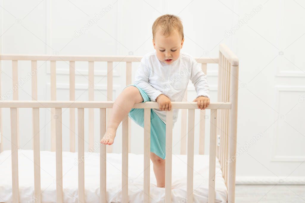baby climbs out of the crib, baby boy 2 years old in the crib.