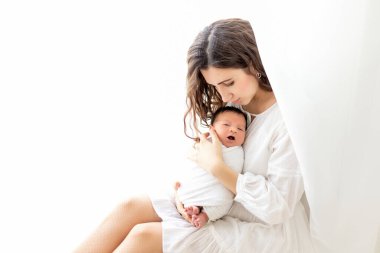 Anne yeni doğmuş bebekle pencerede otururken, anne oğluyla mesajlaşırken.