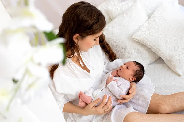 a mother holds a newborn baby on a white background, hugs her son for 7 days, family day, mother\'s love and care.