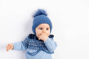 Kışlık şapkalı gülümseyen küçük bir çocuk yalan söylüyor ve kameraya bakıyor. 6 aylık, kışlık giysiler içinde bir çocuğun portresi..