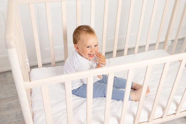 baby 2 years old is sitting in the crib and waiting for his mother.