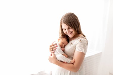 Yeni doğmuş bir bebek annesinin kollarında uyur, yakın plan, çocuğun sessiz uykusu.