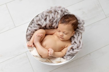 Yeni doğmuş bebek kozanın içinde çıplak uyuyor.