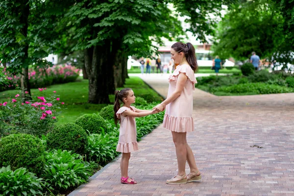 Happy mother and daughter 5-6 years old walk in the Park in the summer, mother talks to her daughter, the concept of a happy family, the relationship of mother and child