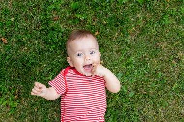 Çekici beyaz kız yeşil çimlerde sırtüstü uzanmış kahkahalarla gülüyor..