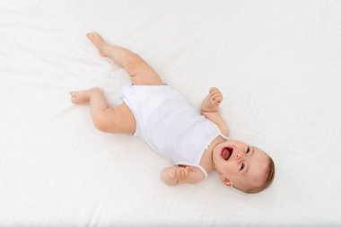 Bebek 6 aylık bebek, bebek odasında sırt üstü yatar. Bebek maması konsepti.