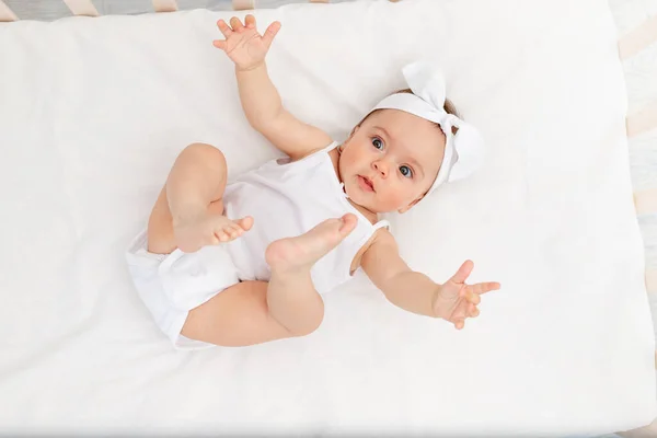6个月大的女婴躺在儿童房的婴儿床里 双手靠在旁边 看着摄像机 婴儿的早晨 婴儿产品的概念 — 图库照片