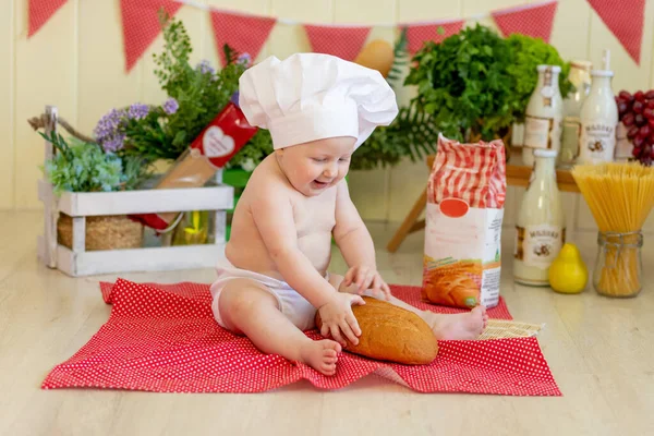 a baby in a cook's hat sits in a beautiful photo zone with flour and vegetables, a baby cook, a child with flour and bread prepares food